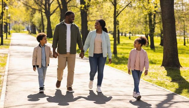 Sunlit Family Walk Holding Hands on Park Path During Golden Hour