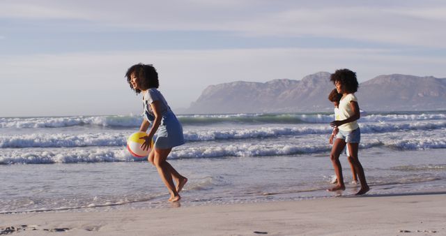 African american mother and her children playing with a ball on the beach. family outdoor leisure time by the sea.