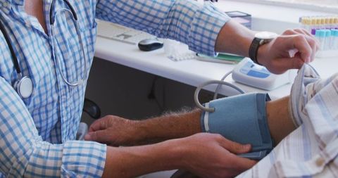 Doctor Checking Senior's Blood Pressure at Clinic