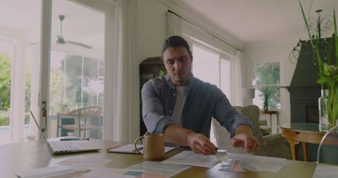 Man managing documents and call in home office setup