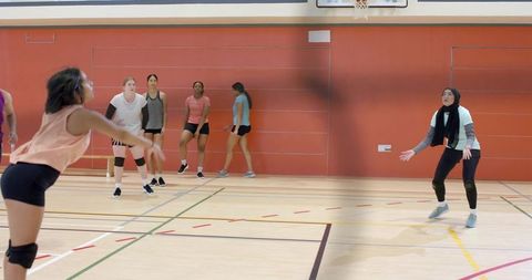 High school women practicing volleyball on indoor court showing teamwork and inclusion