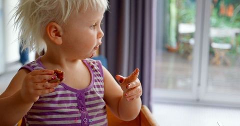 Toddler Eating Messy Snack at Home in Striped Shirt
