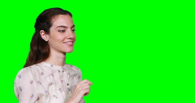 Smiling woman posing against green screen background, wearing a light blouse with a patterned design. This image is ideal for projects that require easy background editing, such as marketing, advertising, digital content creation, and video production.
