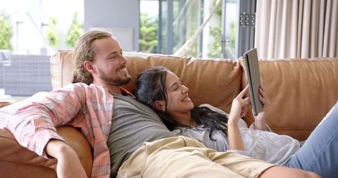Happy Couple Relaxing on Sofa and Sharing Fun with Tablet