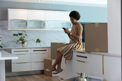 Woman in Stylish Kitchen Using Smartphone Among Moving Boxes