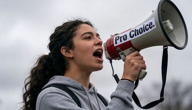 Young activist shouting into pro choice megaphone during outdoor rally under overcast sky