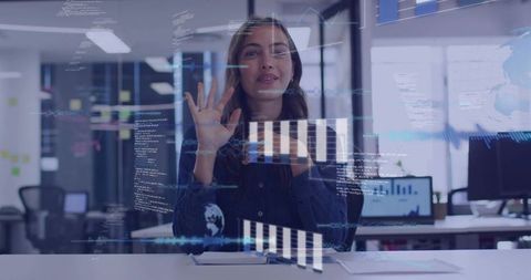 Woman interacting with holographic analytics on transparent display in modern office