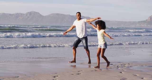 Father and daughter playing on beach during summer. Suitable for themes like family vacations, joyful moments, parental bonding, outdoor fun, and lifestyle content. Perfect for use in advertisements, travel brochures, parenting articles, and social media posts.