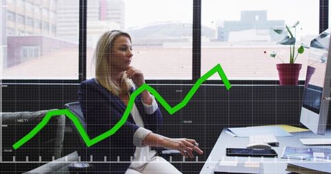 Businesswoman analyzing rising green stock chart on desktop in modern urban office