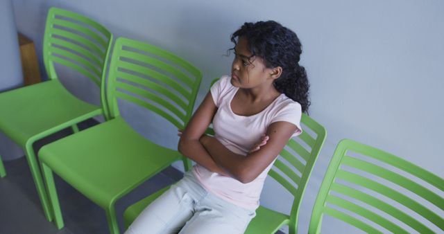 African american girl with arms crossed sitting on a chair at hospital. healthcare and medical concept