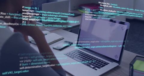 Developer Reviewing Code on Laptop at Desk with Smartphone and Notepad