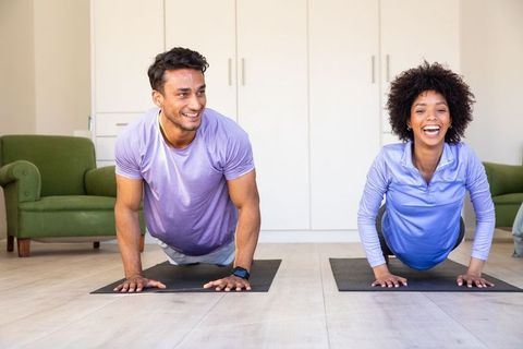 Smiling Multiracial Friends Doing Yoga Planks in Modern Living Room