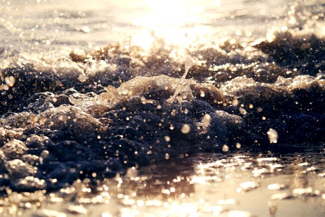 Sunlit waves crashing on a sandy beach with warm golden light reflecting on the water, perfect for travel advertisements, nature enthusiasts, blog articles on beach vacations, and backgrounds for inspirational quotes.
