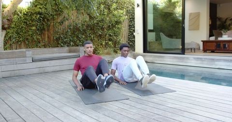 Male Friends Performing Core Exercises by Pool in Leisure Center
