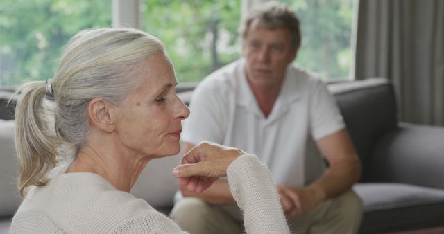 Thoughtful Senior Woman Sitting on Couch with Older Man in Background - Download Free Stock Images Pikwizard.com