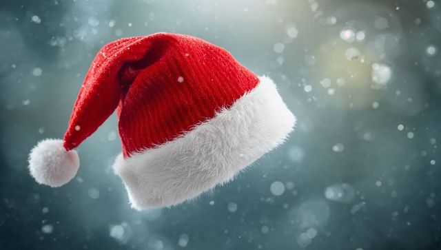Floating red Santa hat glowing in snowy bokeh, knit texture and fluffy white pompom
