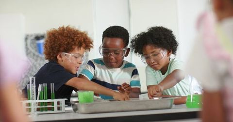 African american boys collaborating on hands-on science experiment wearing safety goggles