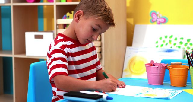 Cute little boy colouring in classroom in playschool 