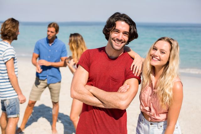 Portrait of happy couple standing by friends on shore at beach