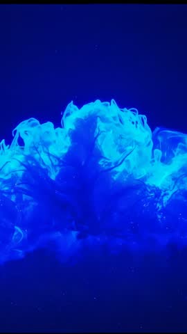 Vertical video showing fluorescent blue mushroom plume forming in lab fluid under UV