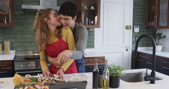 Couple enjoying quality time cooking in a modern kitchen, laughing and hugging. The scene is perfect for promoting a positive and loving home environment, relationship counseling, lifestyle blogs, or kitchen appliance advertisements.