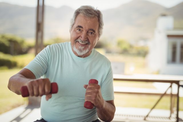 Smiling senior man exercising with dumbbells - Download Free Stock Photos Pikwizard.com