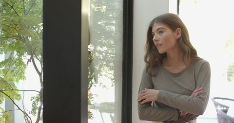 Woman Gazing Through Window in Modern Minimalist Room with Tree View