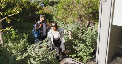 Diverse Couple Walking Upstairs with Luggage in Nature Setting