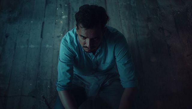 Contemplative man in moody atmosphere on worn wood floor