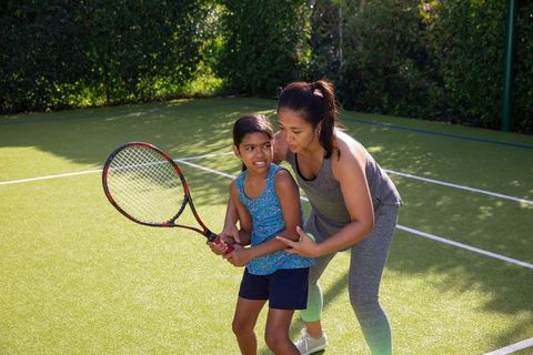 Mother Coaching Daughter on Tennis Court Family Bonding