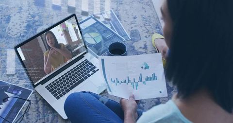 Woman reviewing analytics report while attending video meeting from home, remote teamwork