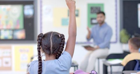 Student raising hand in engaging classroom environment