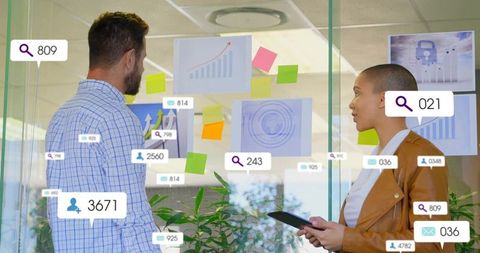 Business team analyzing augmented reality dashboards on glass wall with tablet