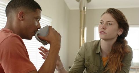 Diverse couple sharing thoughtful conversation over coffee in sunlit modern kitchen