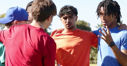 Teen soccer team huddling showing unity and grit during sunny practice session