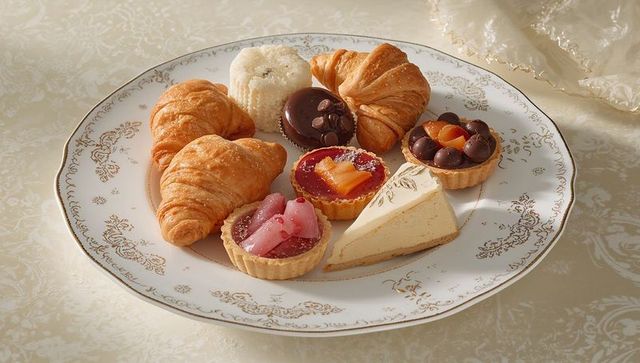 Featuring gold-trim china plate with croissants, cheesecake and fruit tarts on cream damask cloth