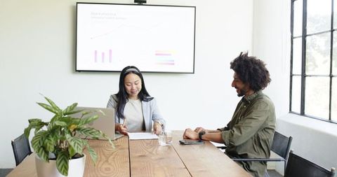 Diverse executive meeting with data presentation and agreement forming