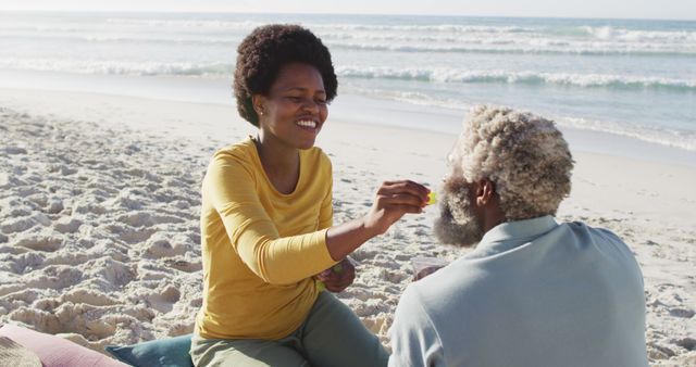 Happy african american couple having picnic on sunny beach. healthy and active time beach holiday.