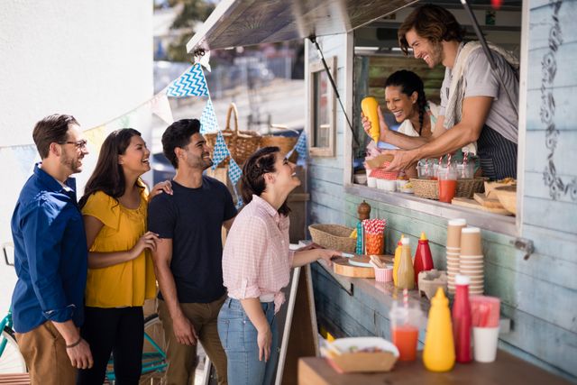 Smiling waiter giving order to customers at counter in food truck van
