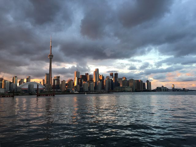 Beautiful view of Toronto skyline in evening light with dramatic clouds above reflecting in water. Ideal for travel brochures, urban backgrounds, and city tourism promotions.