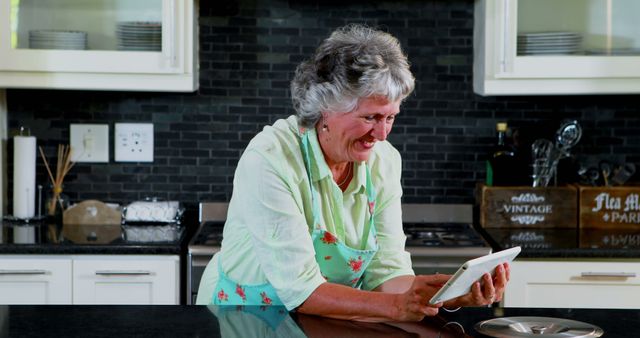 Smiling senior woman using tablet in modern kitchen - Download Free Stock Images Pikwizard.com