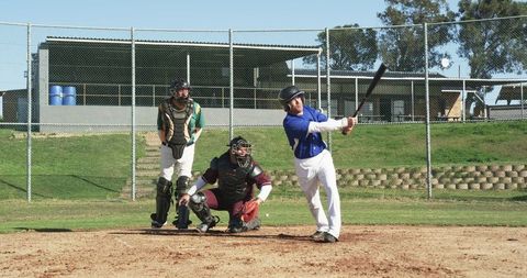 Athlete swinging baseball bat on pitching diamond in action