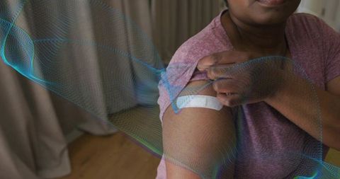Mature woman showing vaccination bandage on upper arm after injection