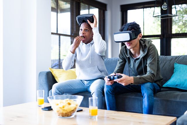 Diverse teenage male friends with vr headsets playing video games at home. Hanging out with friends and spending quality time together concept.