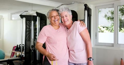 Senior lgbtq couple embracing and measuring waist in home gym