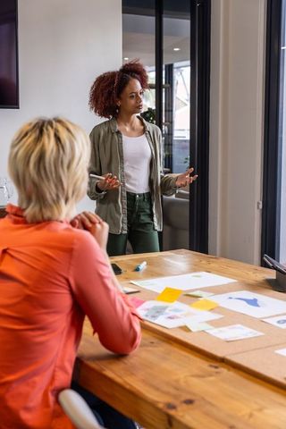 Female coworkers collaborating on design mockups in modern office