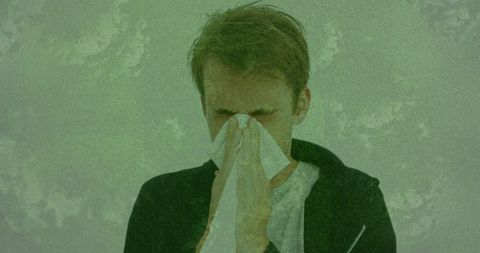 Man sneezing with covid-19 virus overlay