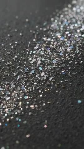Vertical Macro Video Revealing Shimmering Iridescent Glitter Trail Sliding Across Dark Canvas