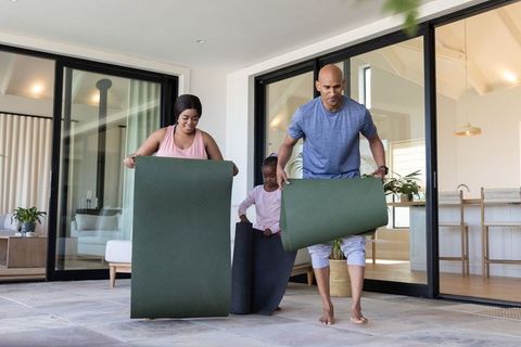 Multiracial family unrolling yoga mats on patio for outdoor morning wellness routine