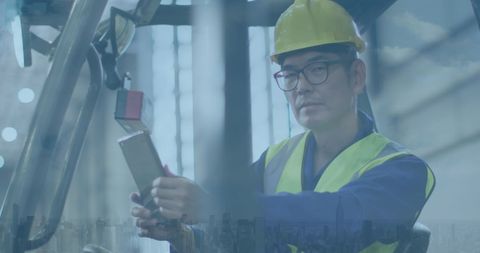 Asian Male Engineer Operating Industrial Machinery with Focus